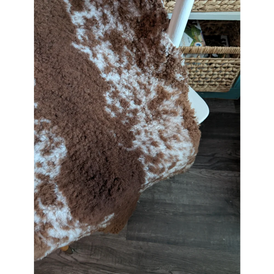 Brown and white fluffy highland spotted grade b sheepskin rug with natural textured surface perfect for cozy decor