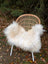 A cozy natural white icelandic sheepskin with long wool draped over a woven wicker chair with metal legs