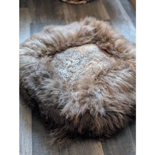 Cozy highland sheepskin pet bed with long wool fur texture in earthy tones