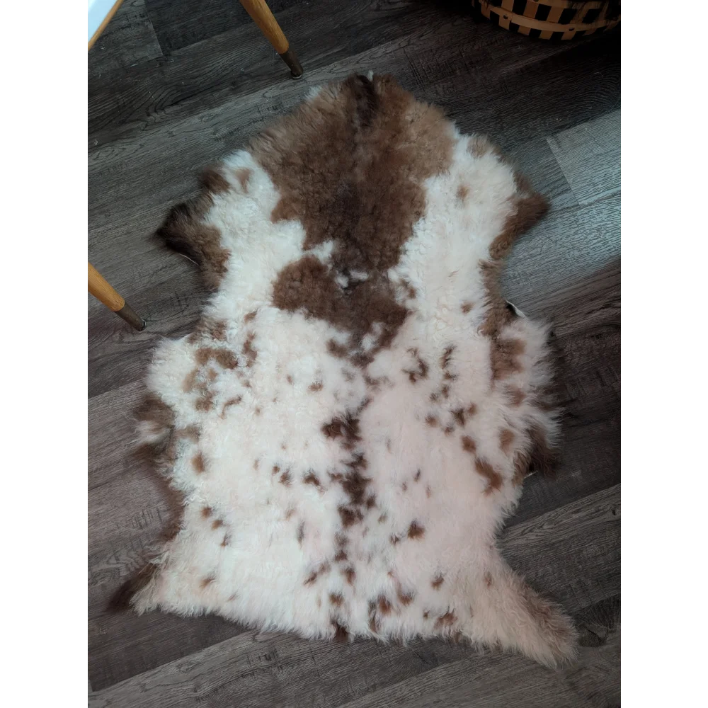 A plush grade a- highland spotted sheepskin rug with soft white and brown speckled natural wool texture