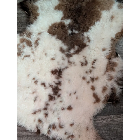 A plush grade a- sheepskin rug with a soft white base and brown patches from the highland spotted collection