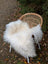 Large long wool natural white icelandic sheepskin throw draped over woven rattan chair with white metal legs