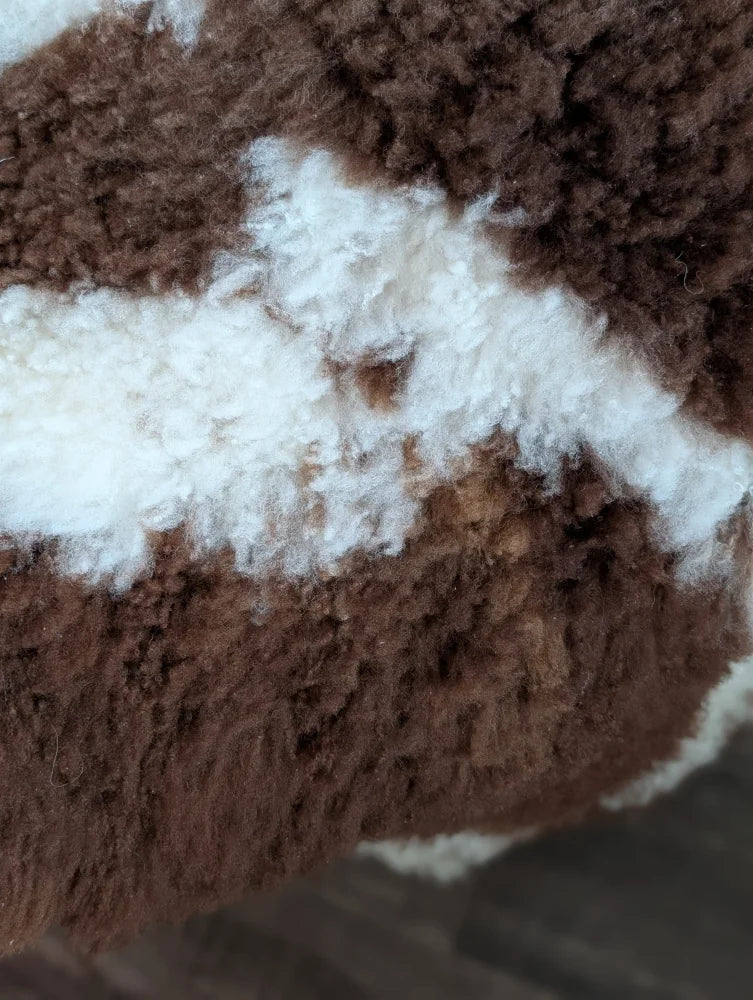 Brown and white fluffy highland spotted grade a- sheepskin fabric with a plush textured appearance