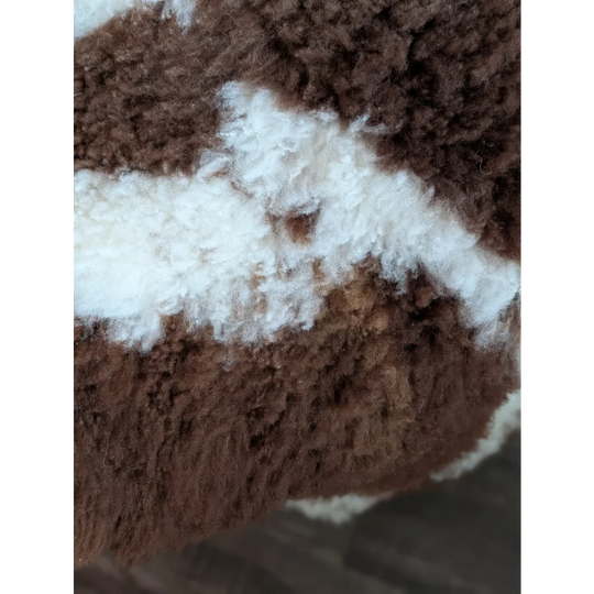 Brown and white fluffy highland spotted grade a- sheepskin fabric with a plush textured appearance
