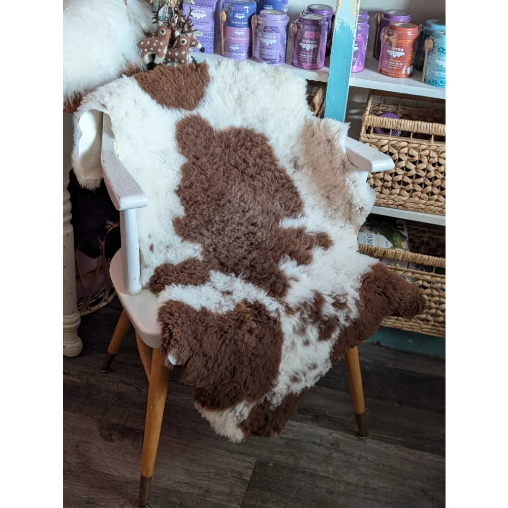 Brown and white highland spotted grade a- sheepskin rug draped over chair adds cozy rustic charm