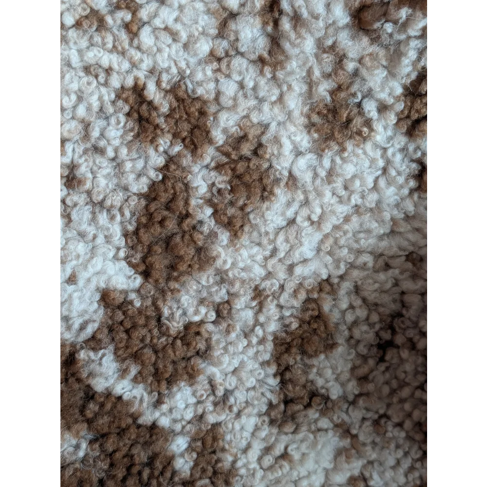 Cream and brown curly fiber knit fabric showing plush texture of grade a- highland spotted sheepskins