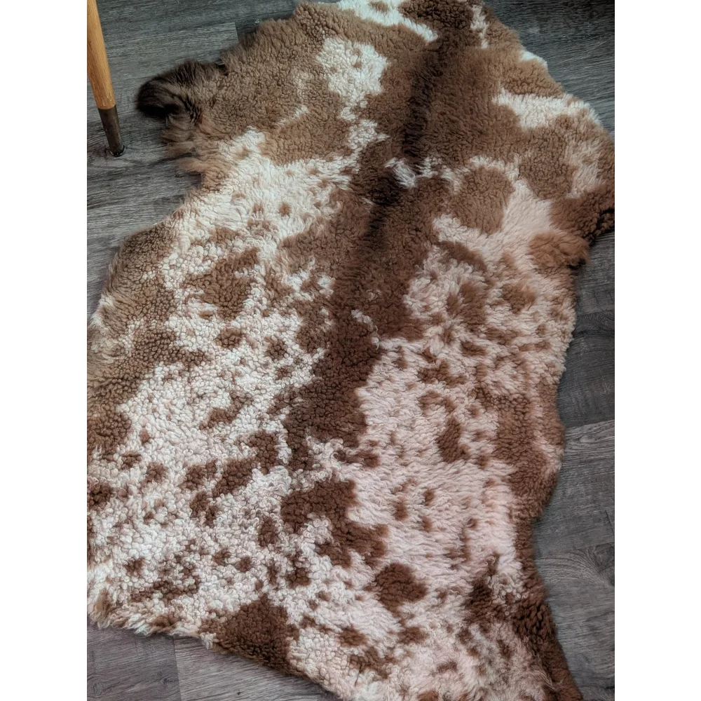A plush grade a- highland spotted sheepskin rug with natural brown and cream speckled pattern in irregular shape