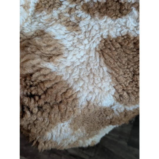A cozy plush highland spotted sheepskin blanket grade a- with creamy white and warm tan textured sections