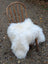 A plush natural white icelandic sheepskin rug with long wool draped over a wooden chair