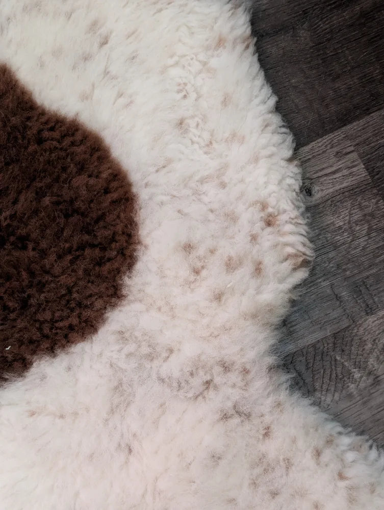 White and brown highland spotted sheepskin rug with fluffy textured surface grade a- sheepskins for cozy decor