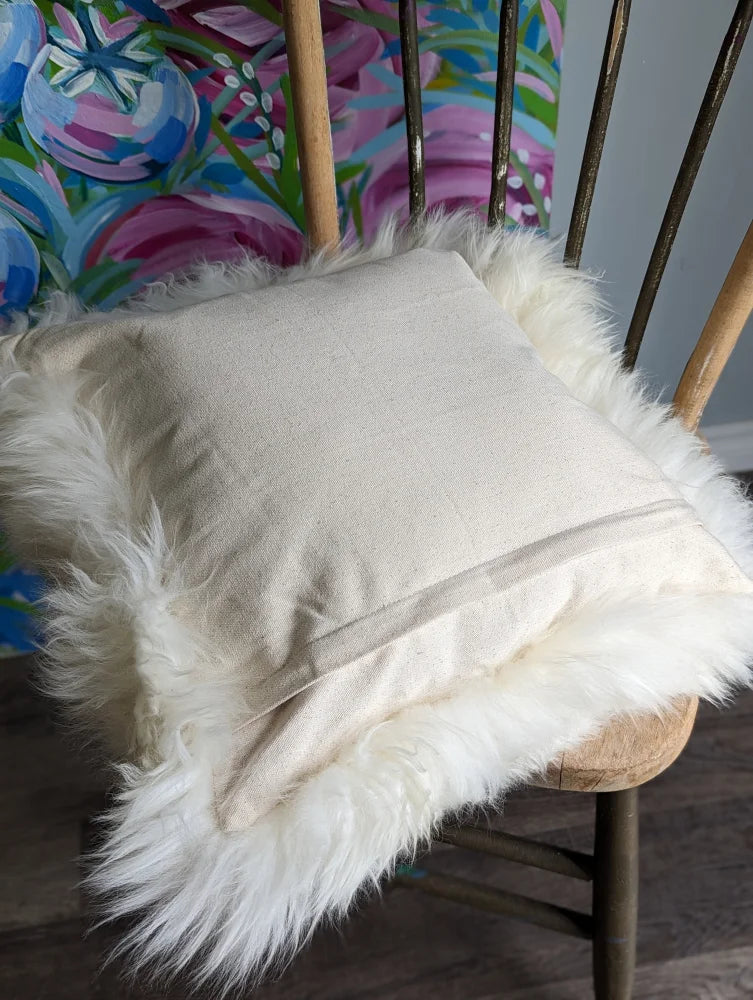 Cozy white merino sheepskin cushion with faux fur pom-poms and zipper