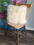 Cozy white merino sheepskin cushion on wooden chair with floral backdrop