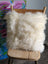 Cream-colored merino sheepskin cushion on wooden chair with floral art