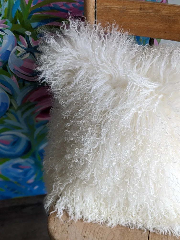 White fluffy Mongolian sheepskin cushion on wooden chair