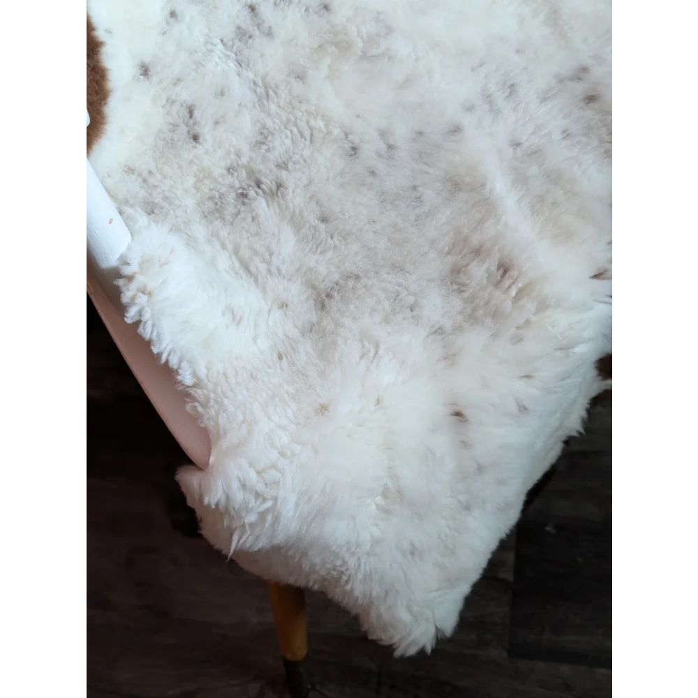 A plush white tibet highland spotted grade a- sheepskin rug with soft fluffy texture and subtle brown speckles