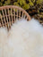 White fluffy natural white icelandic sheepskin long wool throw draped over a woven wicker chair