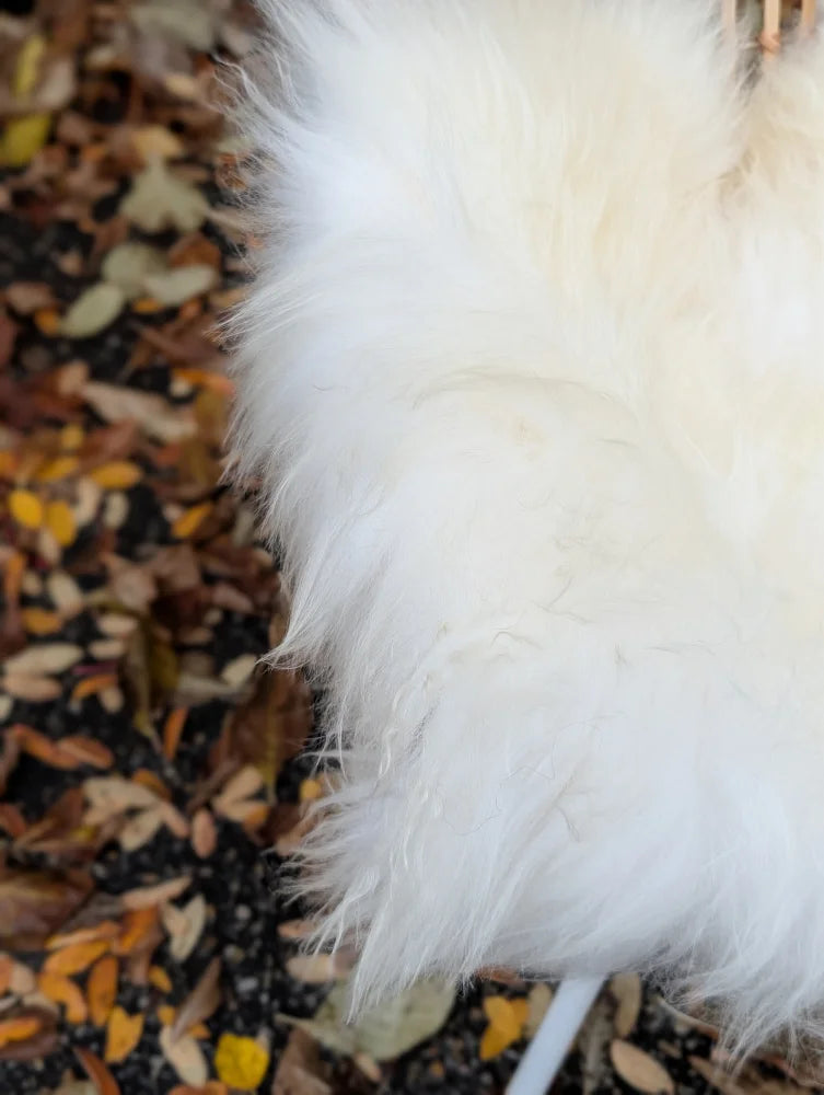 A plush sleeve of a natural white icelandic sheepskin coat with long wool and soft voluminous texture