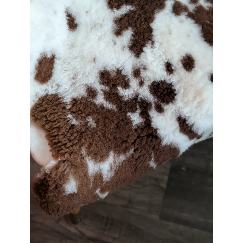 A plush brown and white cow print blanket made from grade a- tibet highland spotted sheepskins with soft fuzzy texture
