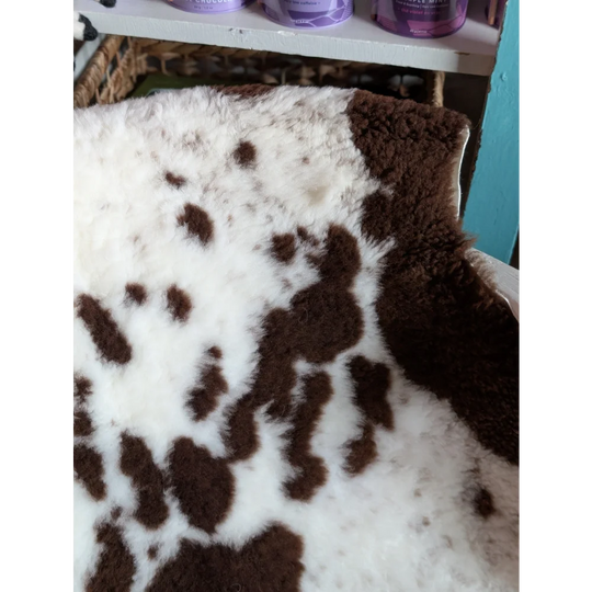 A plush white and brown tibet highland spotted grade a- sheepskin rug with soft fluffy texture