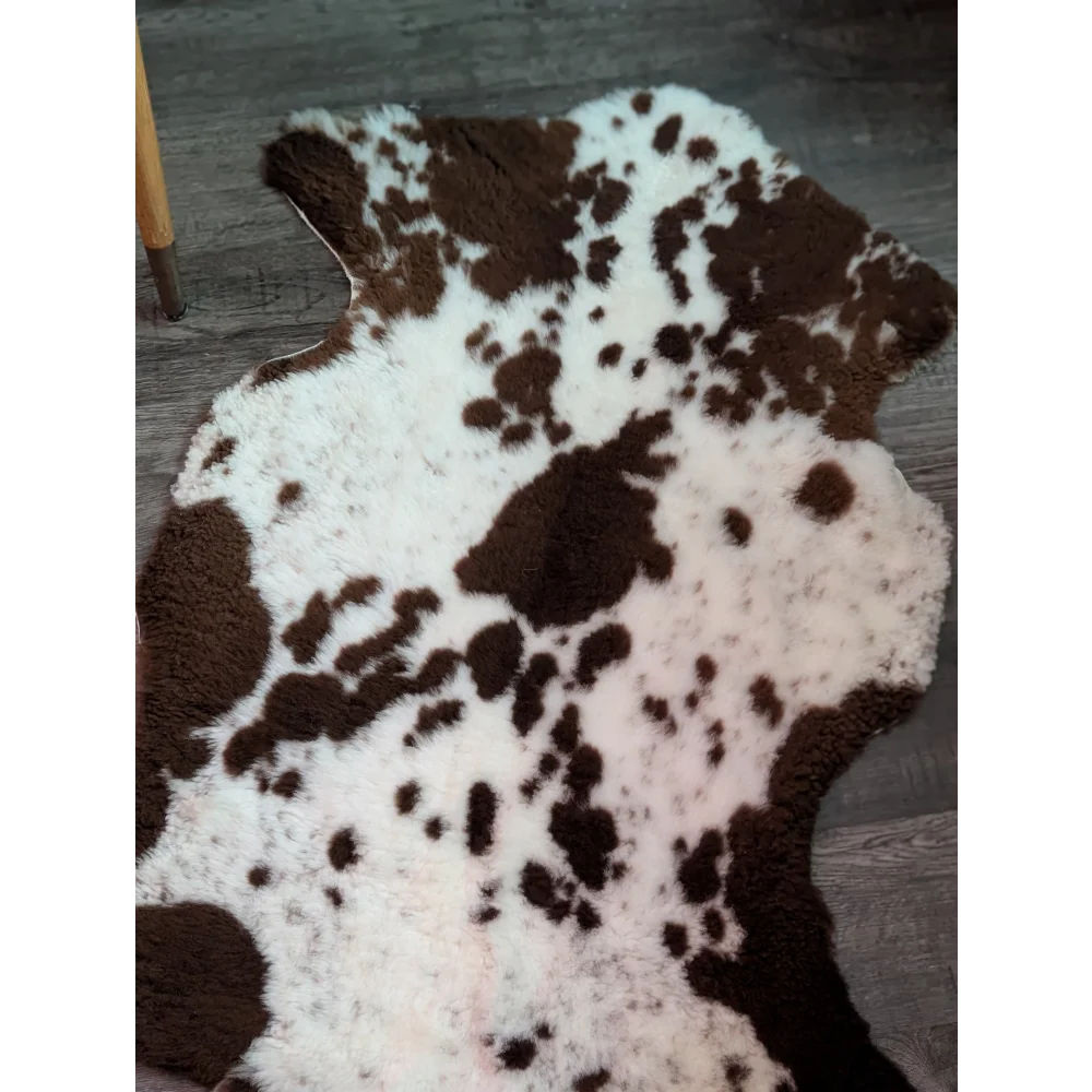A plush tibet highland spotted grade a- sheepskin rug with irregular brown and white cow print pattern