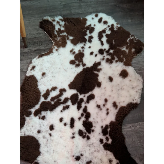 A plush tibet highland spotted grade a- sheepskin rug with irregular brown and white cow print pattern
