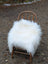 White fluffy large long wool natural white icelandic sheepskin chair cover draped over a rustic wooden chair