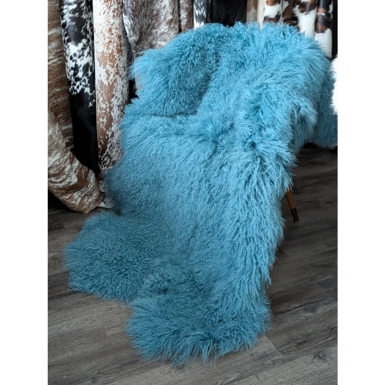 Vibrant aqua 72x48 inch Mongolian sheepskin rug draped on chair