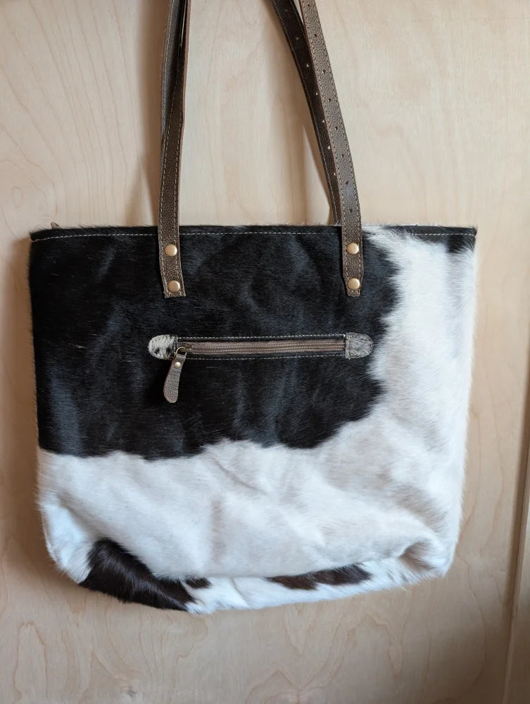 Black and white real cowhide tote bag with brown leather straps and gold hardware perfect for everyday use