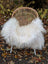 A cozy natural white icelandic sheepskin with long wool draped over a woven rattan chair with metal legs