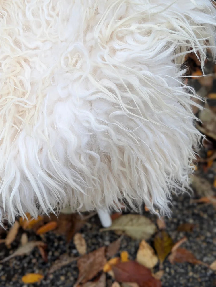 A plush natural white icelandic sheepskin cushion with long wool and soft voluminous texture