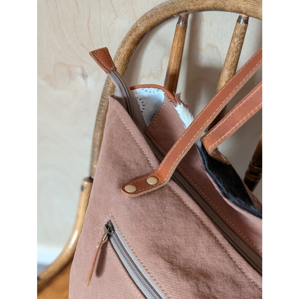 A spacious oakley specks canvas tote bag in soft rose with real cowhide straps and zipper closure showing white lining