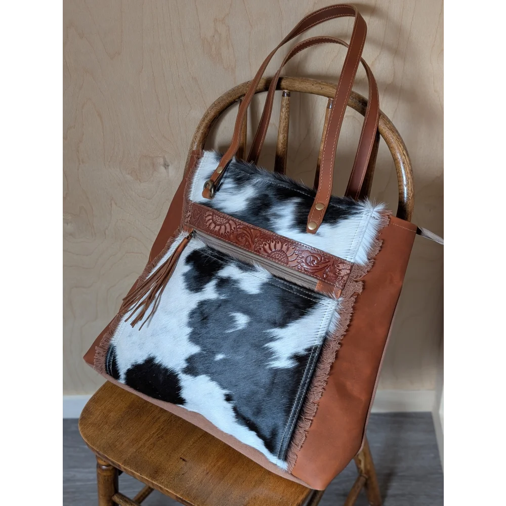 Brown leather oakley bag with real cowhide black and white patchwork, fringed edges, and embossed zipper pull