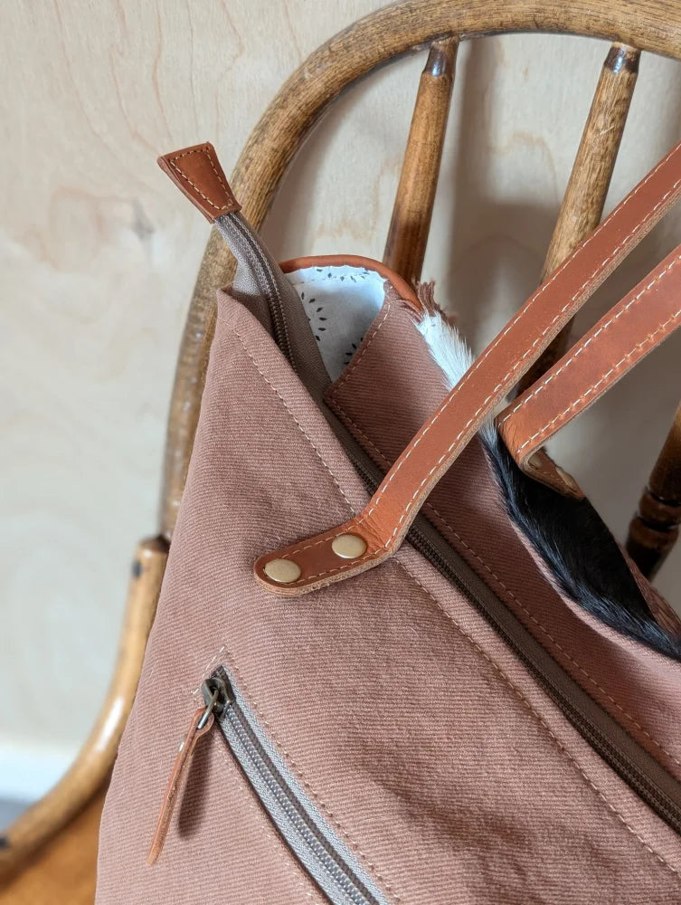 A spacious oakley specks canvas tote bag in soft rose with real cowhide straps and zipper closure showing white lining