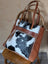 Brown leather oakley bag with real cowhide black and white patchwork, fringed edges, and embossed zipper pull