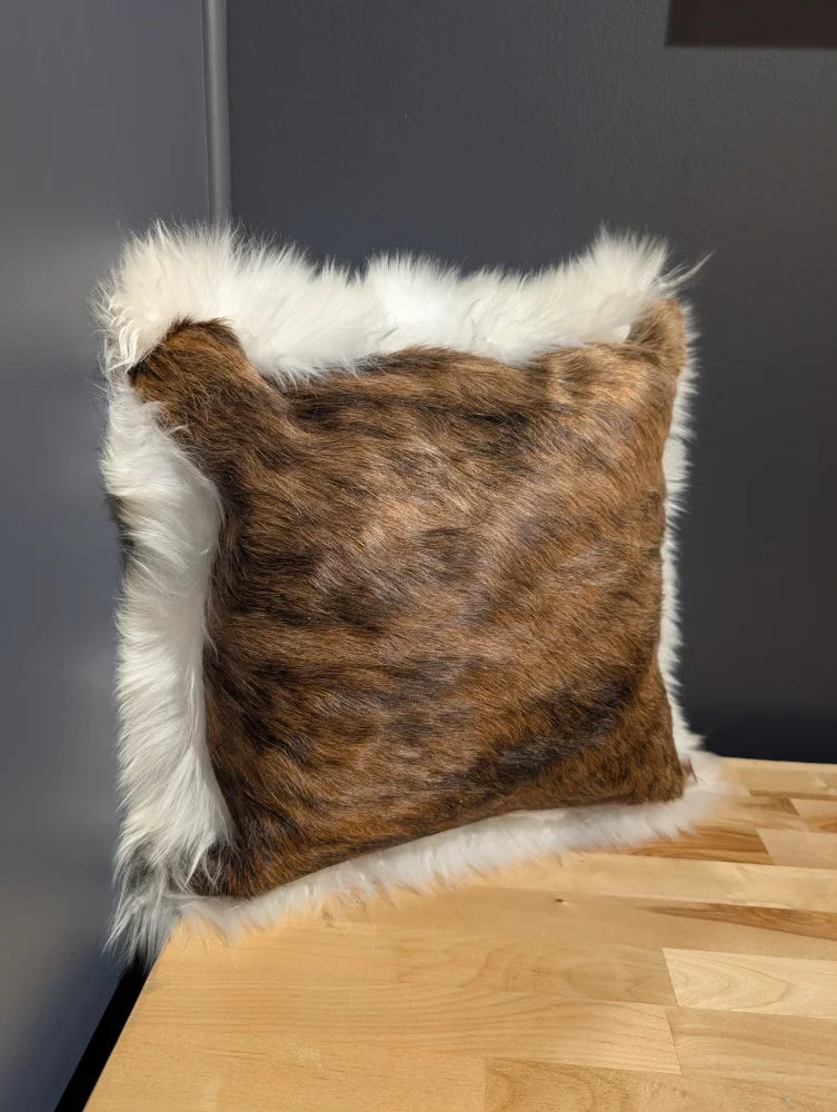 Brown and white fur throw pillow with plush textured surface made of cowhide merino sheepskin cushion