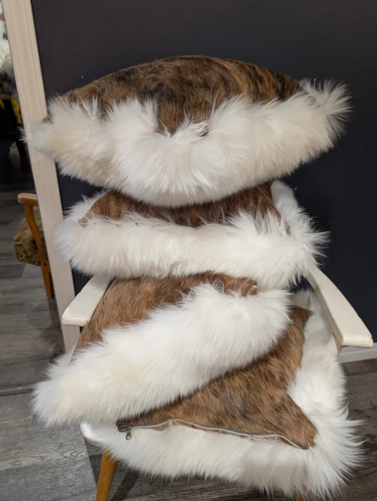 Stacked brown and white cowhide merino sheepskin cushions with plush textured surface for cozy decor