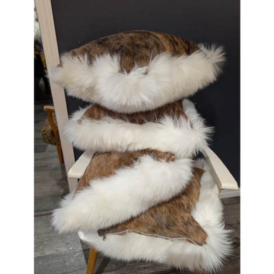 Stacked brown and white cowhide merino sheepskin cushions with plush textured surface for cozy decor