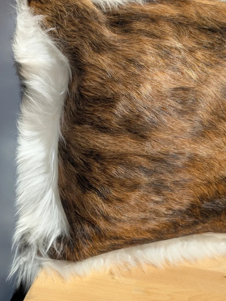 Brown and white cowhide merino sheepskin cushion with plush natural fur texture and one of a kind design