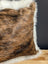 Brown and black cowhide merino sheepskin cushion with plush white fur trim for cozy home decor
