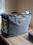 #2 the sunflower weekender bag is a gray canvas cartwright hand-tooled bag with brown leather handles and hair-on hide patch