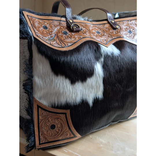 #2 the sunflower weekender bag is a black and white hair-on hide tote with tan cartwright hand-tooled leather and brown handles