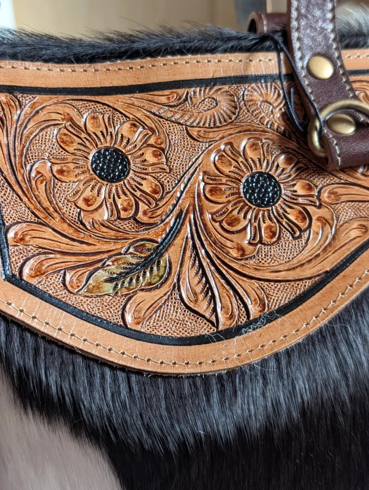 The sunflower weekender bag is a tan leather cartwright hand-tooled bag with intricate floral tooling black fur trim and a zippered pocket