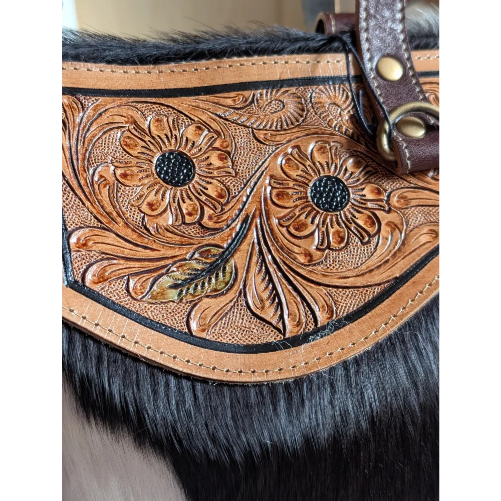 The sunflower weekender bag is a tan leather cartwright hand-tooled bag with intricate floral tooling black fur trim and a zippered pocket