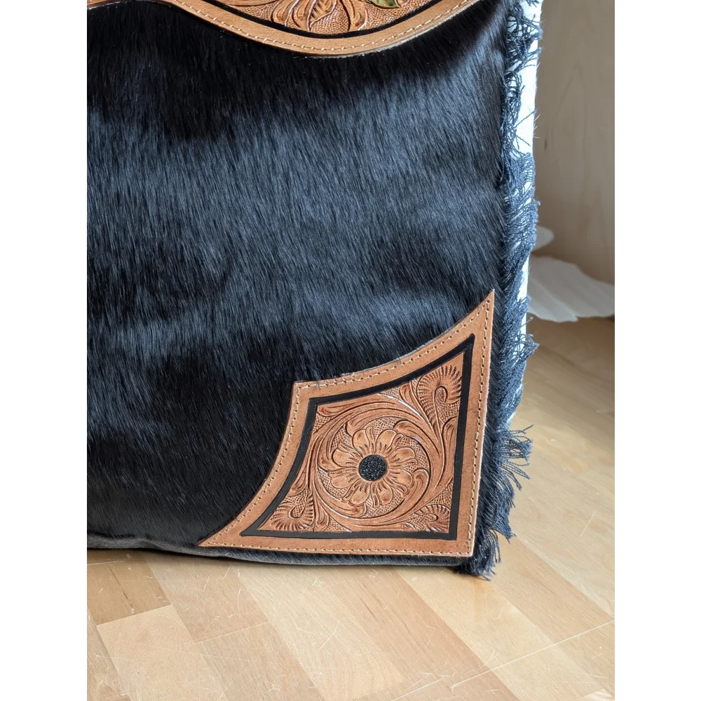 Black cowhide throw pillow with tan leather floral embroidery and frayed edges complements the cartwright hand-tooled bag