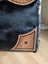 Black cowhide throw pillow with tan leather floral embroidery and frayed edges complements the cartwright hand-tooled bag