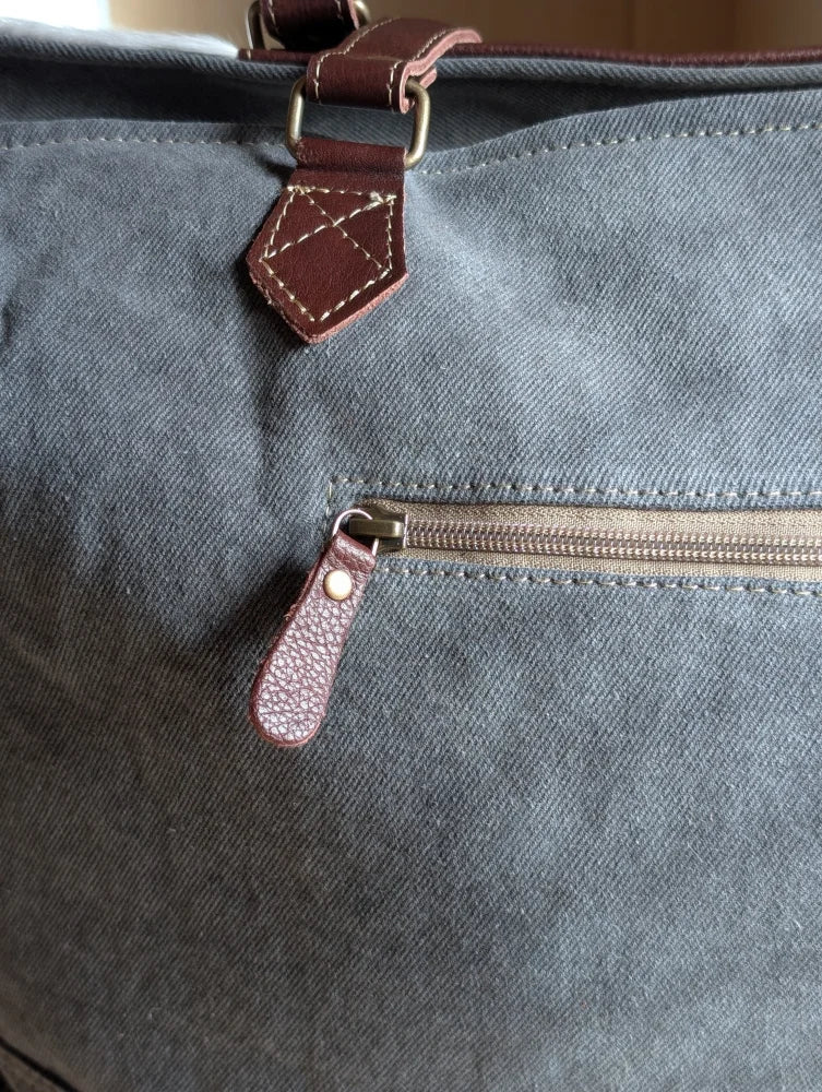 Gray canvas sunflower weekender bag with brown leather accents and zippered pocket, inspired by cartwright hand-tooled bag