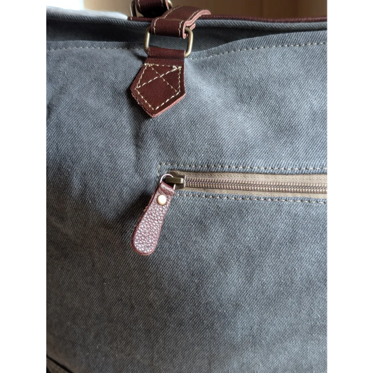 Gray canvas sunflower weekender bag with brown leather accents and zippered pocket, inspired by cartwright hand-tooled bag