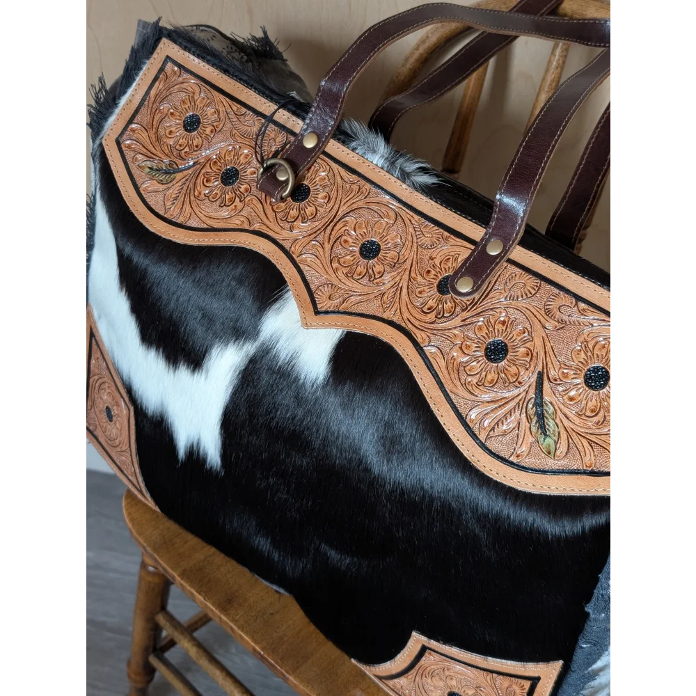 The sunflower weekender bag is a cartwright hand-tooled bag with floral leather, black studs, zippered pocket, and hair-on hide body