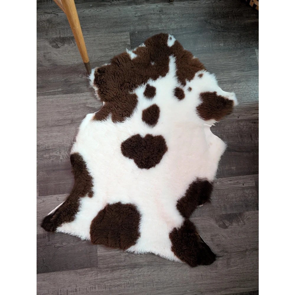 A plush white and brown highland spotted grade a- sheepskin rug with a soft fluffy texture perfect for cozy decor