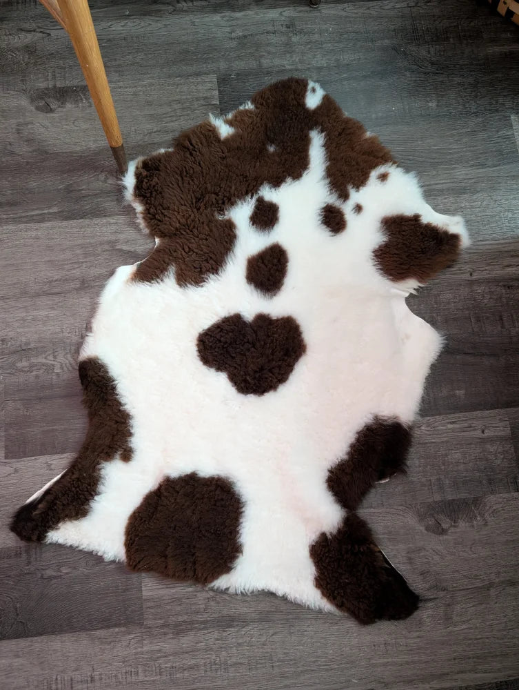A plush white and brown highland spotted grade a- sheepskin rug with a soft fluffy texture perfect for cozy decor